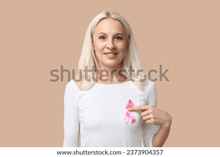 Mature woman with pink ribbon on beige background. Breast cancer awareness concept