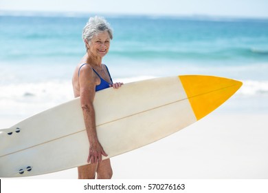 Mature woman posing with a surfboard on the beach - Powered by Shutterstock