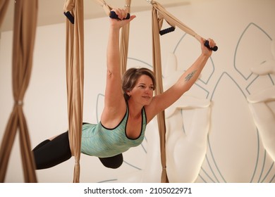 Mature Woman Practicing Aerial Yoga On A Hammock, Doing Superman Pose