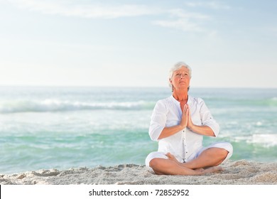 Mature Woman Practicing Yoga On The Beach