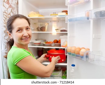 Mature Woman Putting Pan Into Fridge  At Home