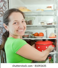 Mature Woman Putting Pan Into Refrigerator  At Home