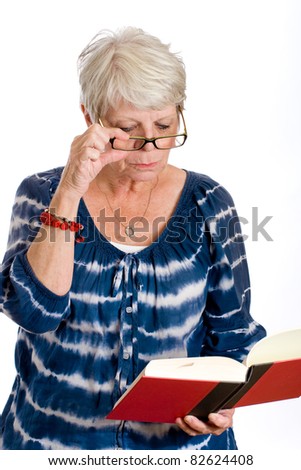 Mature woman reading a book with the help of glasses for her vision.