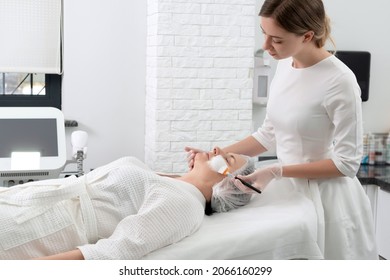 Mature Woman Receiving Wwhte Facial Mask In Spa Beauty Salon. Concept Of Skin Care For Older People