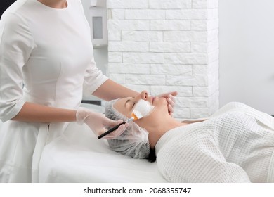 Mature Woman Receiving Wwhte Facial Mask In Spa Beauty Salon. Concept Of Skin Care For Older People