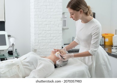 Mature Woman Receiving Wwhte Facial Mask In Spa Beauty Salon. Concept Of Skin Care For Older People