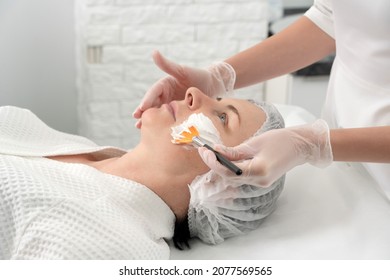 Mature Woman Receiving Wwhte Facial Mask In Spa Beauty Salon. Concept Of Skin Care For Older People