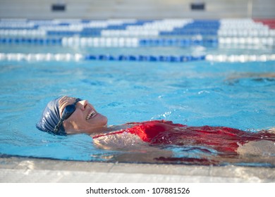 Mature Woman In Red Bathers Doing Swim Exercises, Keeping Healthy And Fit In Swimming Pool.