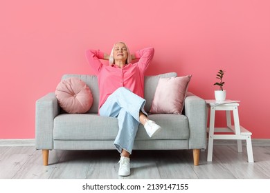 Mature Woman Relaxing On Sofa Near Pink Wall