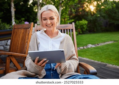 Mature woman relaxing outdoors using digital tablet in garden - Powered by Shutterstock