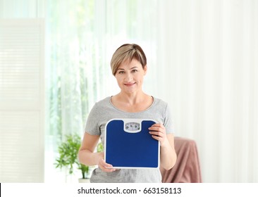 Mature Woman With Scales At Home. Weight Loss Concept