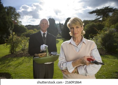 Mature Woman With Secateurs By Butler With Basket Of Gardening Tools, Portrait