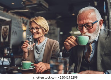 mature woman and a senior man couple engage in conversation while have cup of coffee warmth and camaraderie relish the simple pleasure of good company creating memories in setting of the cafe - Powered by Shutterstock