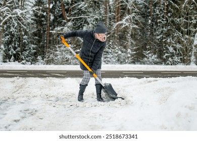 Mature woman shoveling snow in a backyard on winter day. Winter chores. - Powered by Shutterstock