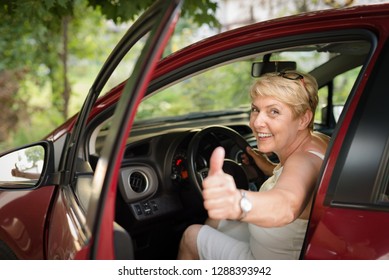 A mature woman shows her thumb up, she is happy because of her pass exam to driving test