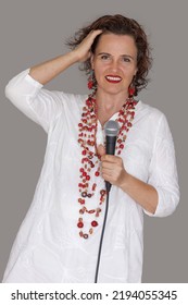 Mature Woman Singing Into Microphone, Isolated On Gray Background, Studio.