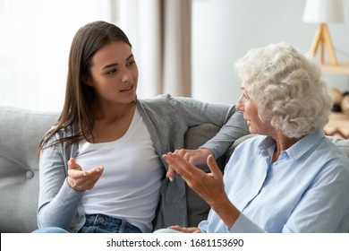 Mature Woman Sit On Couch In Living Room Talk Chat With Grown-up Adult Daughter At Home, Millennial Girl Have Pleasant Conversation With Elderly Middle-aged Mother, Share Secret, Gossip Indoors