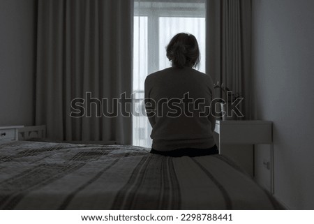 Mature woman sitting alone in the room, sad depressed person. Back view. mental health