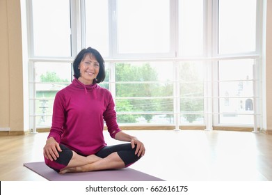 Mature Woman Sitting On The Floor In Lotus Position. Healthy Fitness Concept With Active Lifestyle.