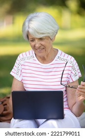 Mature Woman Sitting On Park Bench With Laptop