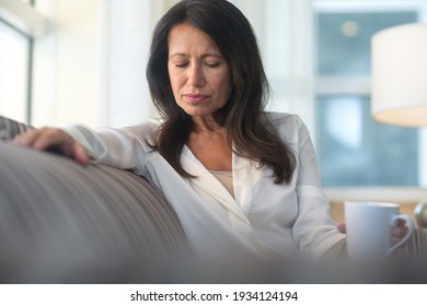 Mature Woman Sitting On The Sofa Feeling Sad And Alone.