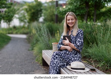 Mature Woman Sitting In Park Bench, Enjoying Time For Herself.