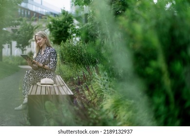 Mature Woman Sitting In Park Bench, Enjoying Time For Herself.