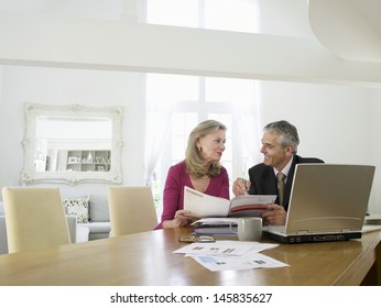 Mature Woman Sitting At Table With Financial Advisor