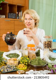  Mature Woman Sitting At The Table With Herbal Tea And Herbs