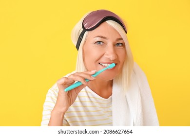 Mature Woman In Sleep Mask And With Toothbrush On Color Background