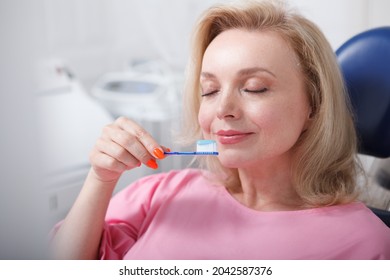 Mature Woman Smelling Toothpaste On Her Toothbrush