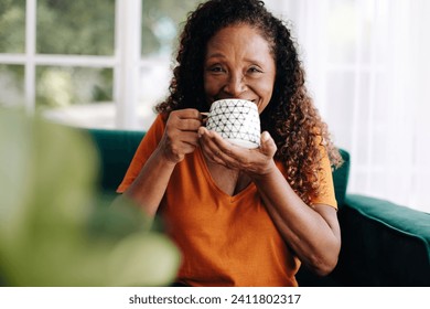 Mature woman spending her time at home after a lifetime of hard work, taking pleasure in the simple joys of life, which include a cozy cup of coffee and a relaxed post retirement lifestyle. - Powered by Shutterstock