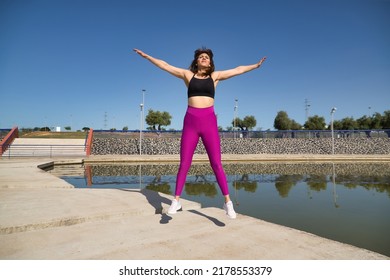 Mature Woman In Sportswear Jumping In The Air Happy In An Outdoor Park. Fitness Concept, Maturity, Relax, Happiness, Jumping.