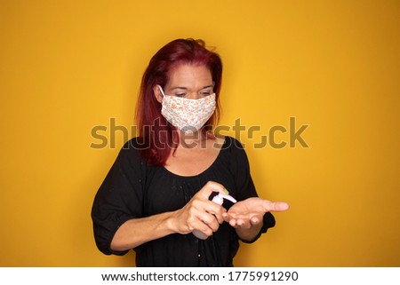 Mature woman is spraying alcohol gel on her hands. Antiseptic cleaning gel in woman hands. Close up. Hygiene during Covid-19 Coronavirus epidemic.