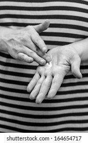 Mature Woman Spread Out Skincare Cream To Her Hand, Vertical Format Black And White Image