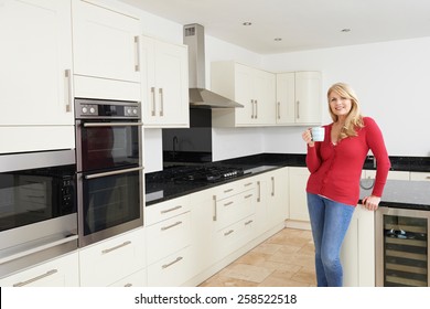 Mature Woman Standing In New Luxury Fitted Kitchen