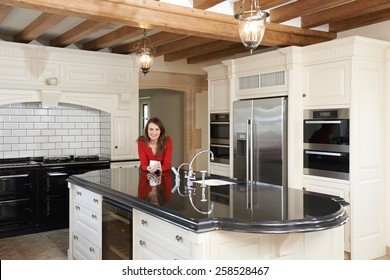 Mature Woman Standing In New Luxury Fitted Kitchen