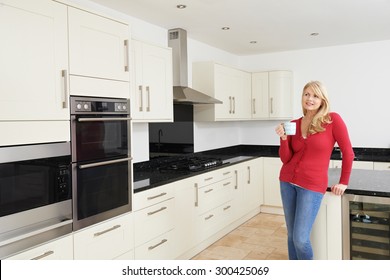 Mature Woman Standing In New Luxury Fitted Kitchen