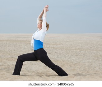 Mature Woman Standing In Yoga Pose At The Beach