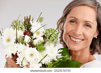 Mature woman, studio and happy with flowers on portrait with confidence for gift or present on white background. Female person, smile and joy or satisfied with roses for appreciation and care - Powered by Shutterstock