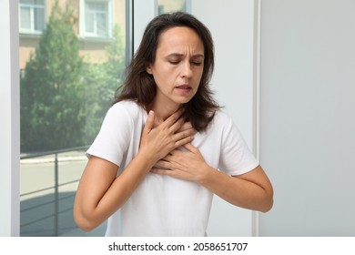 Mature woman suffering from breathing problem near window indoors - Shutterstock ID 2058651707