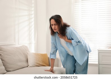 Mature woman suffering from breathing problem at home - Shutterstock ID 2058651725