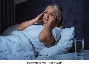 Mature Woman Suffering From Headache In Bed At Night