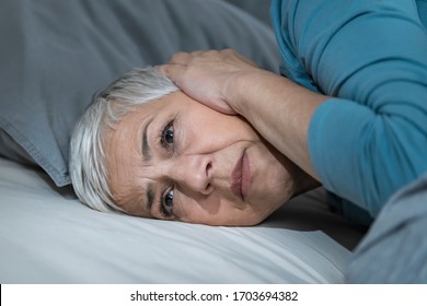 Mature Woman Suffering From Hyperacusis Or Misophonia, Lying In Bed Awake At Night