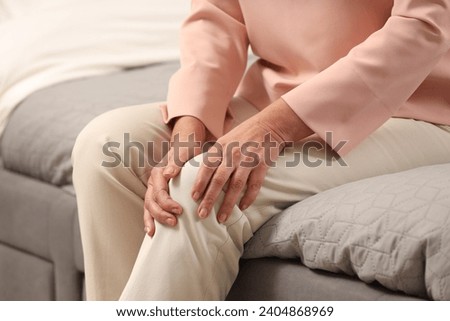 Mature woman suffering from knee pain on bed, closeup. Rheumatism symptom