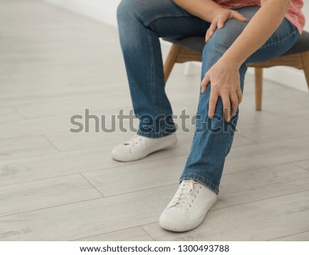 Mature woman suffering from leg pain at home, closeup. Space for text