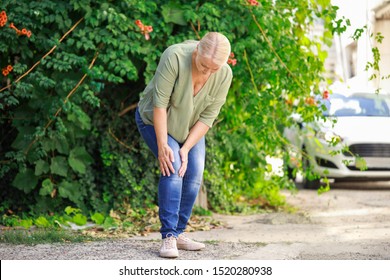 Mature Woman Suffering From Pain In Knee Outdoors