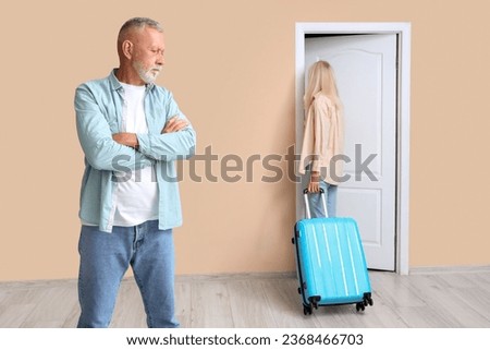 Mature woman with suitcase leaving her husband at door. Divorce concept