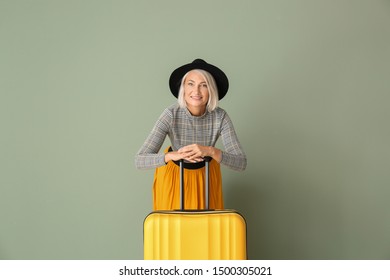 Mature Woman With Suitcase On Color Background