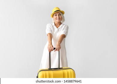 Mature Woman With Suitcase On Light Background